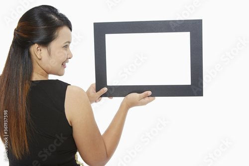 Woman holding up a black picture frame