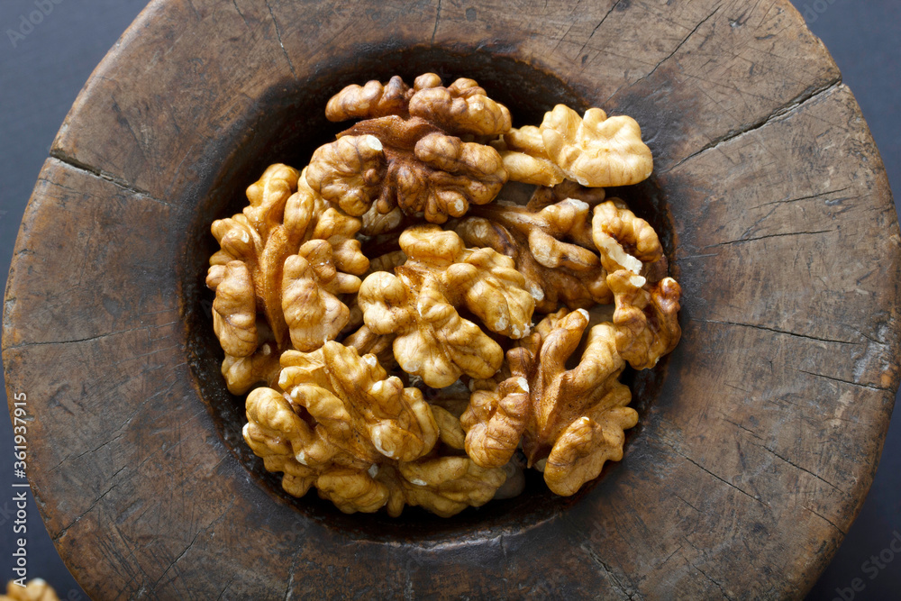 Fototapeta premium Walnuts in antique, wooden mortar.