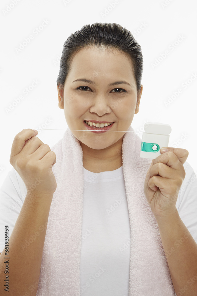Woman smiling and holding up dental floss Woman smiling and holding up dental floss