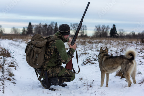 hunter in camouflage clothes ready to hunt, holding gun and walking in forest. hunting and people concept