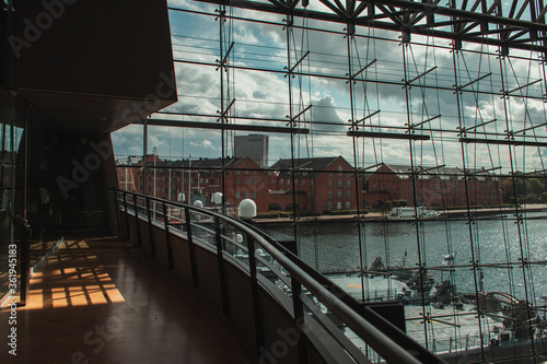 COPENHAGEN, DENMARK - APRIL 30, 2020: Glass facade of Black Diamond Royal Library with ship in harbor at background, Copenhagen, Denmark