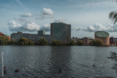 Selective focus of ducks on river with buildings and cloudy sky at background, Copenhagen, Denmark