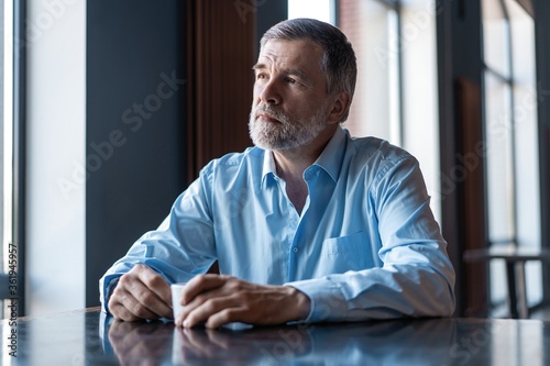 Pensive businessman drinking coffee in cafe and looking away.