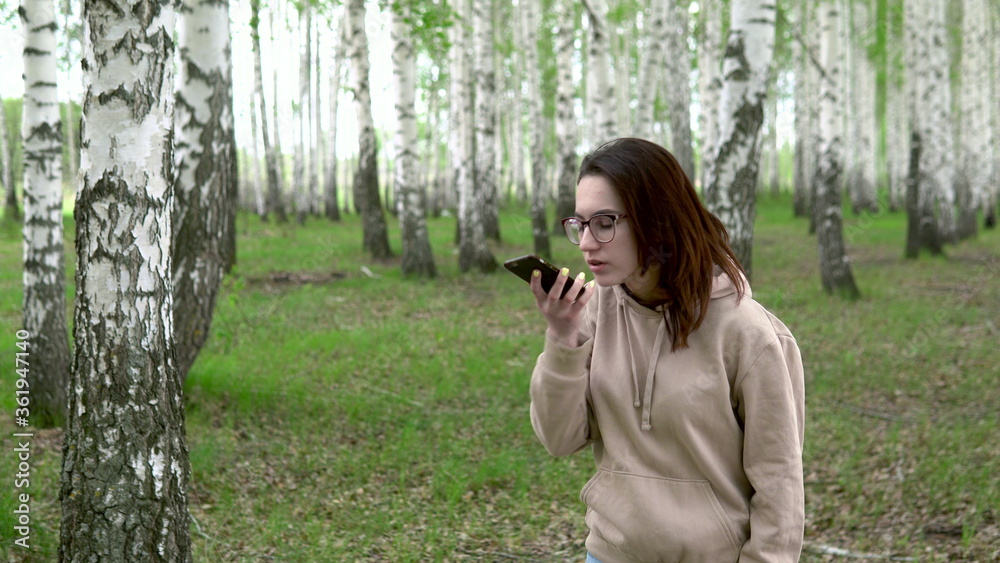A young woman is looking for a cellular network in a birch forest. A girl is talking on the phone, but the connection is interrupted. The woman is nervous. A young woman is looking for a cellular network in a birch forest. A girl is talking on the phone, but the connection is interrupted. The woman is nervous.