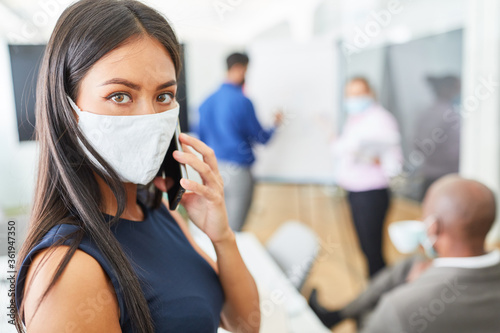 Business Frau mit Mundschutz telefoniert mit dem Handy