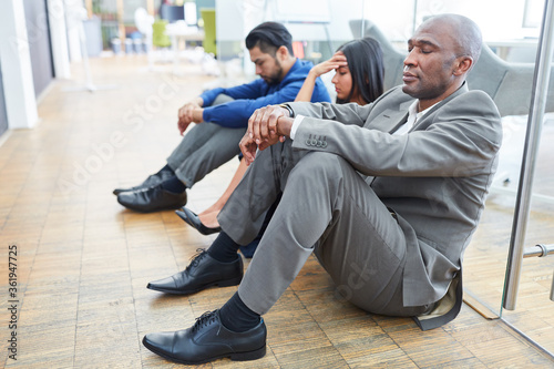Frustrierte Geschäftsleute sitzen auf dem Fußboden im Büro