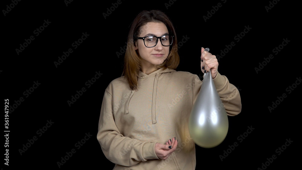 Young woman shakes balls with water. Girl shakes the ball on a black background. The balloon trembles like jelly. Young woman shakes balls with water. Girl shakes the ball on a black background. The balloon trembles like jelly.