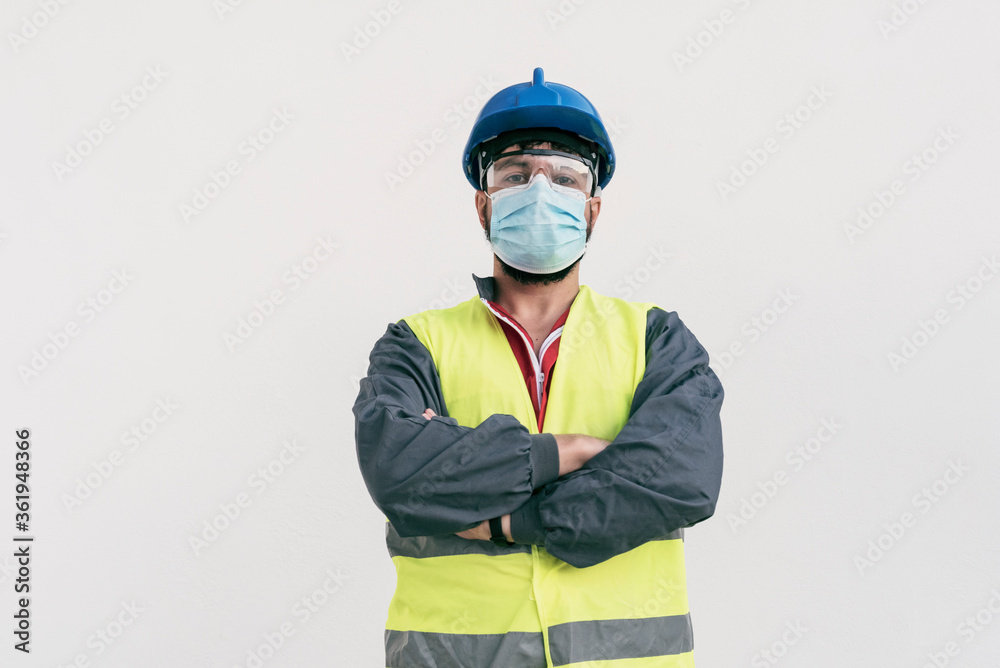 Construction worker portrait on white wall posing with face mask covid -19 prevention Construction worker portrait on white wall posing with face mask covid -19 prevention