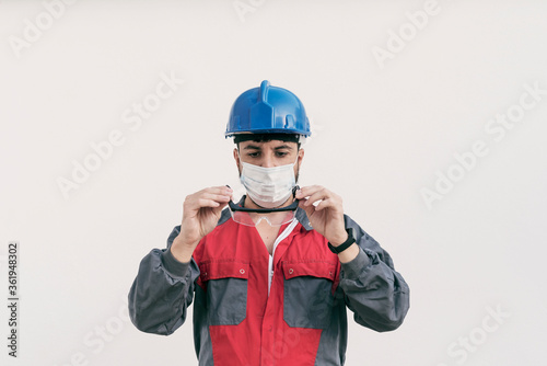 Construction worker portrait on white wall posing with face mask covid -19 prevention