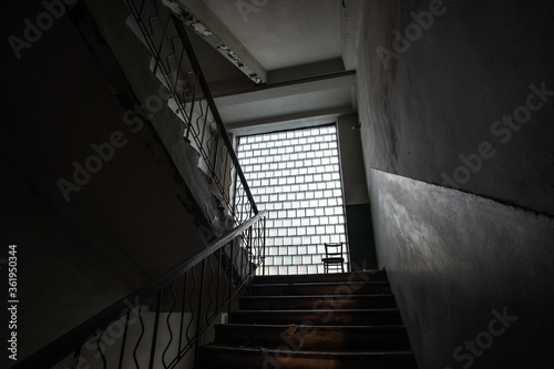Dark interior of staircase of an abandoned building in the style of Soviet brutalism of the 70s.