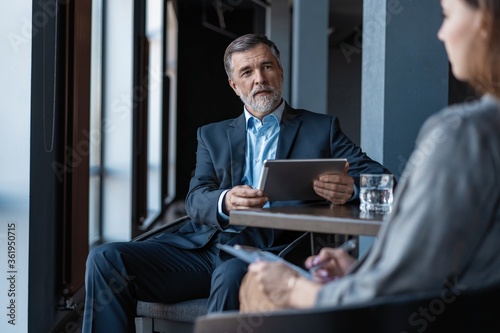 Image of mature businessman interviewing female.