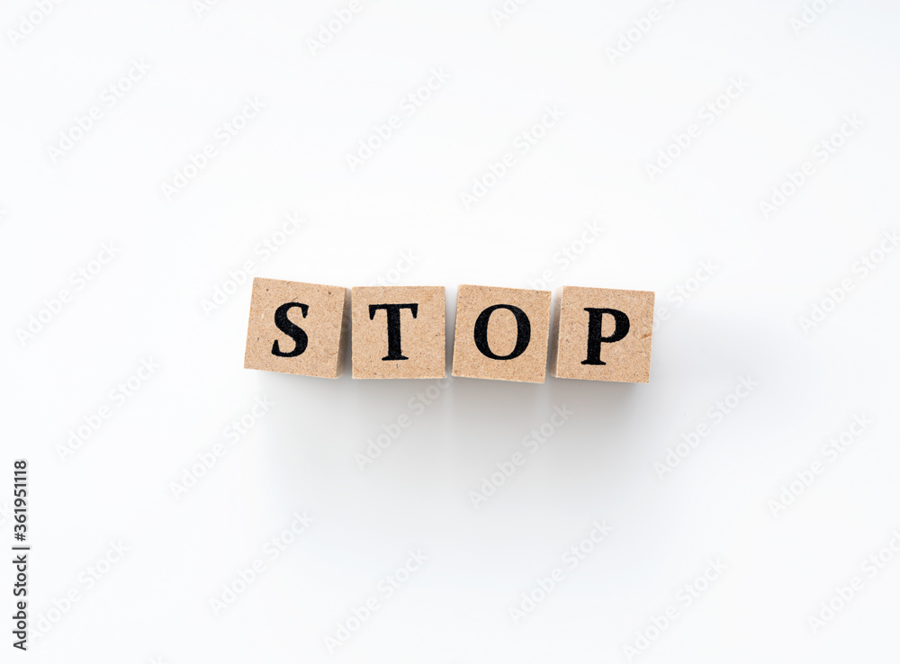 A wooden block with the word STOP written on it on a white background A wooden block with the word STOP written on it on a white background
