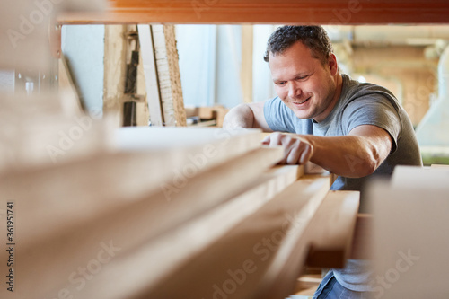 Carpenter in workshop fetches wood from warehouse