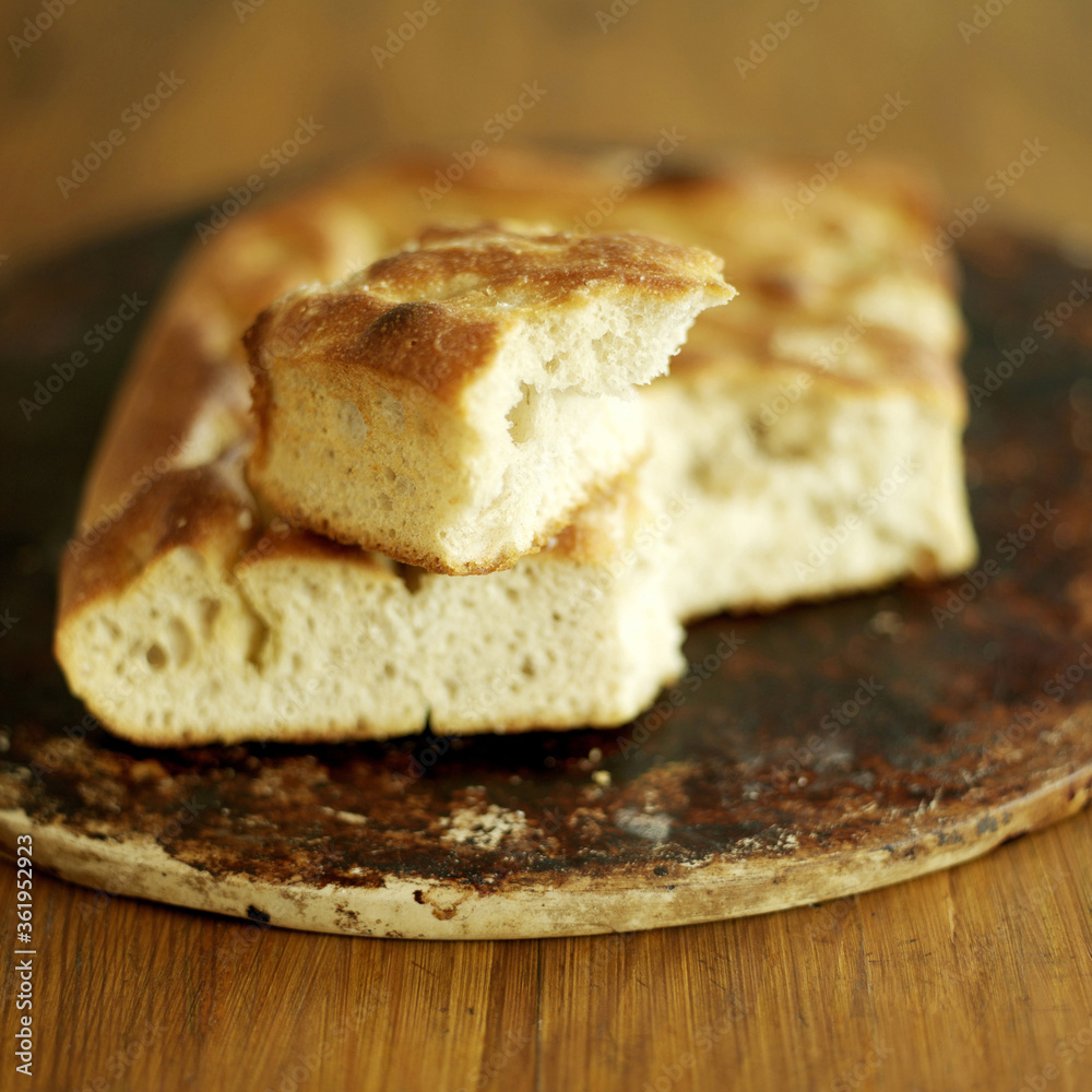 Fresh Italian focaccia bread with broken piece on top Fresh Italian focaccia bread with broken piece on top