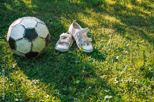 An old soccer ball is lying on a green lawn grass