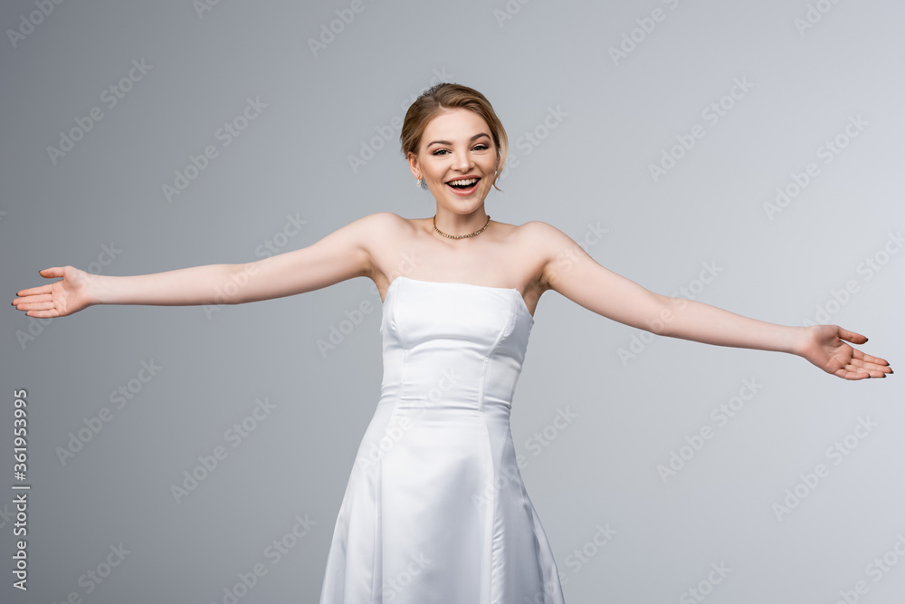 Naklejka premium cheerful bride in white wedding dress with outstretched hands isolated on grey