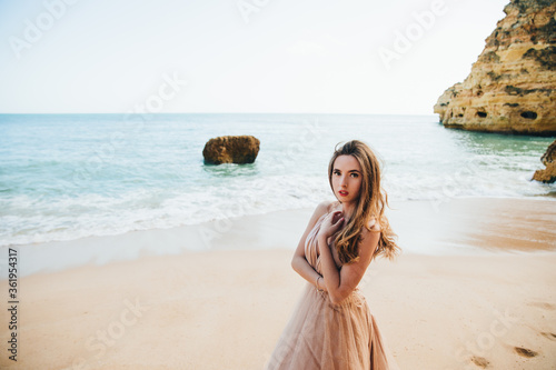 Beautiful woman on the beach. Single girl in long dress. Woman walking barefoot on white sand of tropical island.