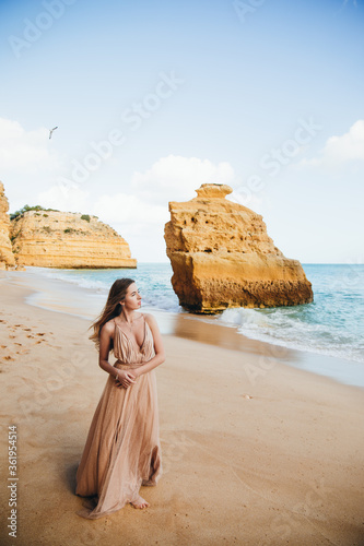 Young female on beach wearing elegant dress. Beautiful Summer Woman on the Beach