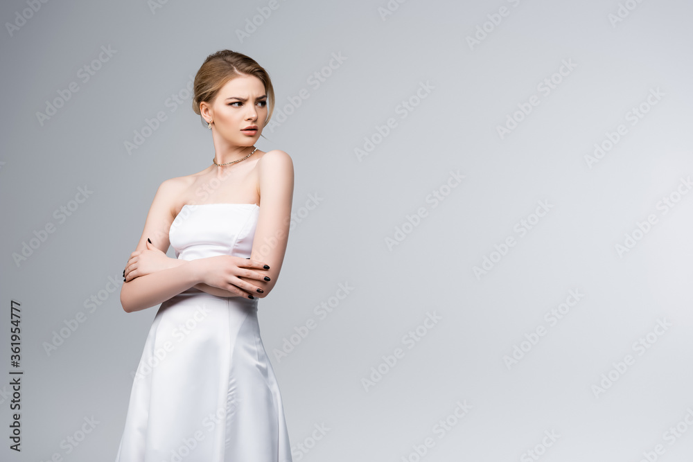 displeased bride in white wedding dress standing with crossed arms isolated on grey displeased bride in white wedding dress standing with crossed arms isolated on grey