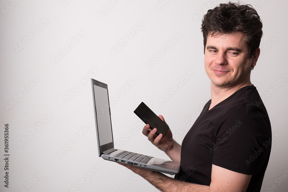 Man works on a laptop with a mobile phone. Happy man talking on a cell phone and laptop. Man works on a laptop with a mobile phone. Happy man talking on a cell phone and laptop.