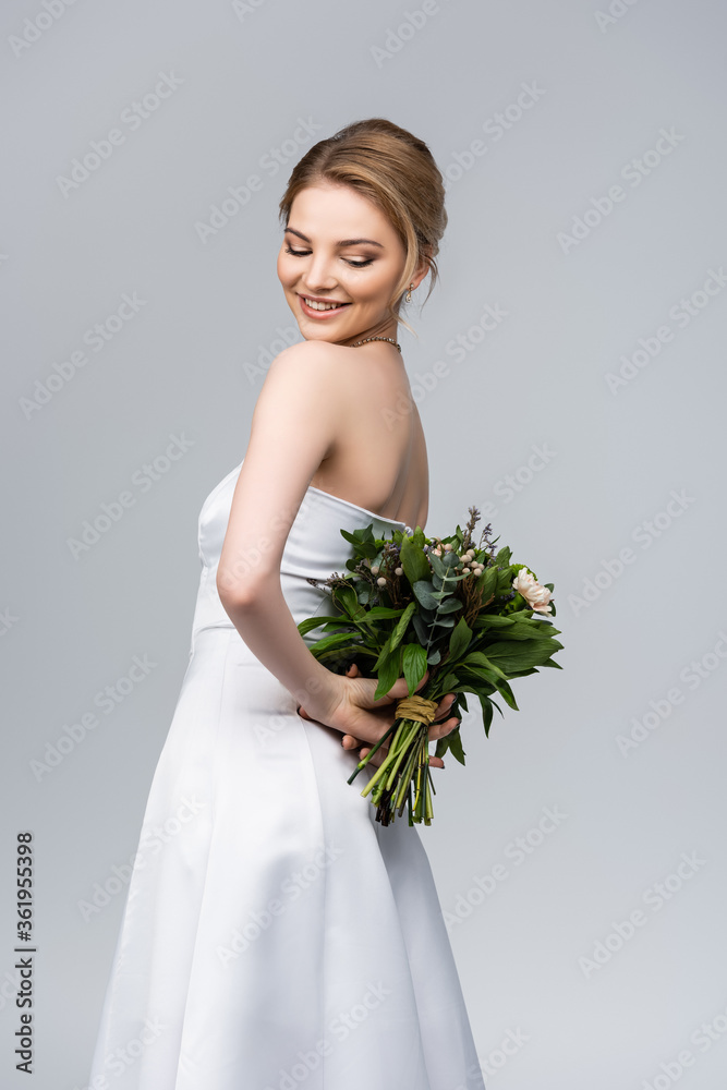 young and cheerful woman in white wedding dress holding bouquet of flowers isolated on grey young and cheerful woman in white wedding dress holding bouquet of flowers isolated on grey