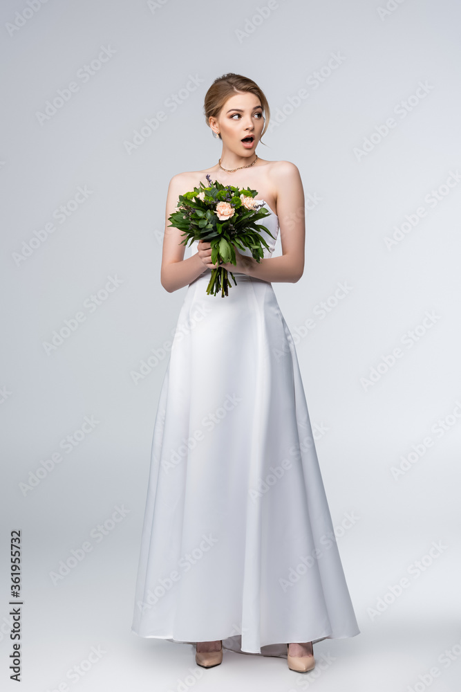 shocked girl in white wedding dress holding bouquet of flowers isolated on grey shocked girl in white wedding dress holding bouquet of flowers isolated on grey