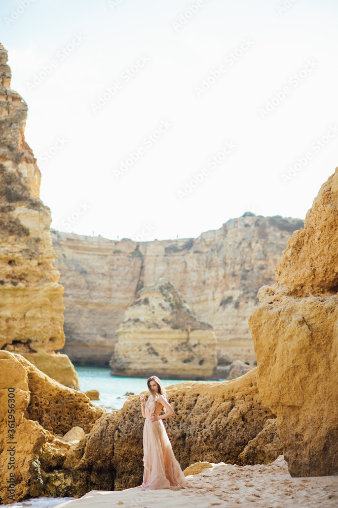 gorgeous style brunette young woman in blue chameleon dress long train standing on a rock near the sea, sand tropical on a rock.beautiful mermaid lonely melancholy waiting freedom and freelancing
