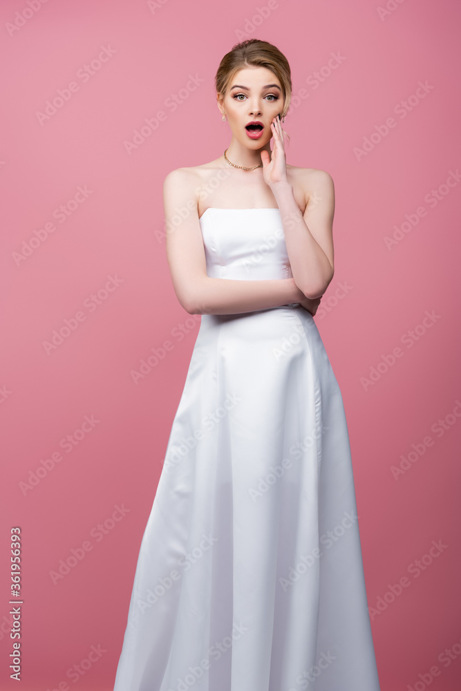 surprised bride in white wedding dress touching face isolated on pink surprised bride in white wedding dress touching face isolated on pink
