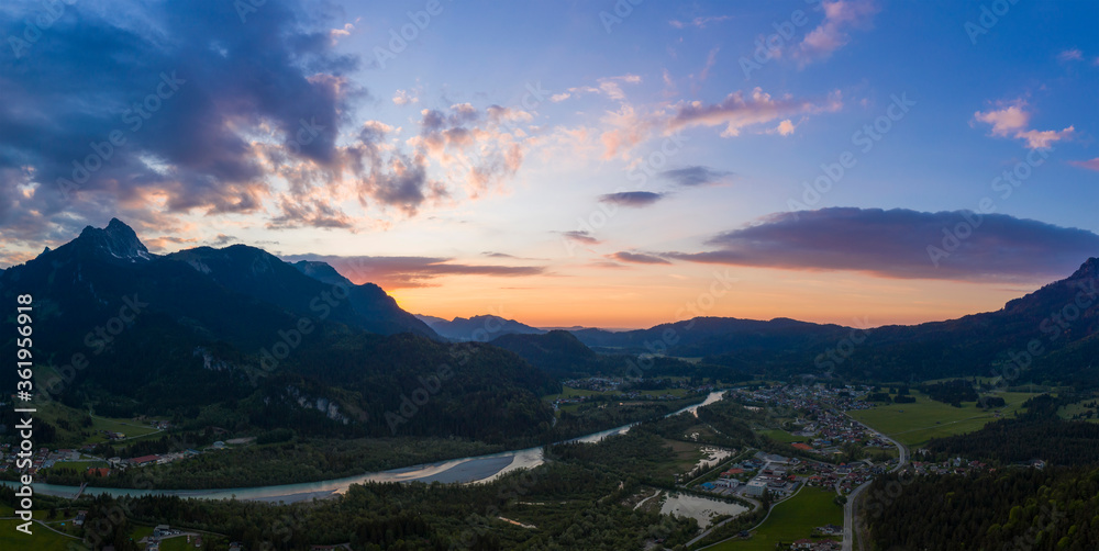 panorama of village pflach in austrian mountains with river lech at colorful sunset