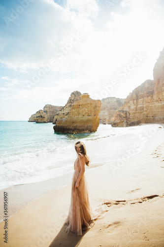 gorgeous style brunette young woman in blue chameleon dress long train standing on a rock near the sea  sand tropical on a rock.beautiful mermaid lonely melancholy waiting freedom and freelancing