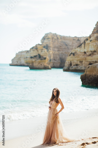 Fashionable bride in elegant wedding dress walking on the coast of ocean. Beauty  emotional  lifestyle concept