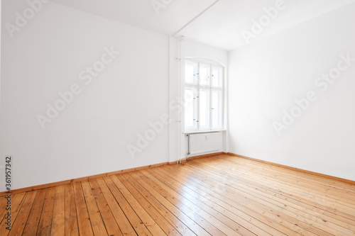 empty white room in apartment flat with hardwood floor and window