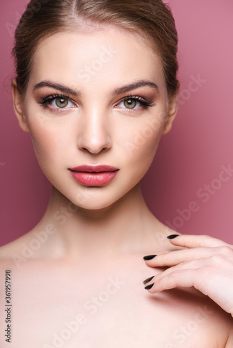 naked and beautiful woman with makeup looking at camera on pink