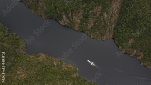 Aerial shot of a boat along a river on a stunning canyon