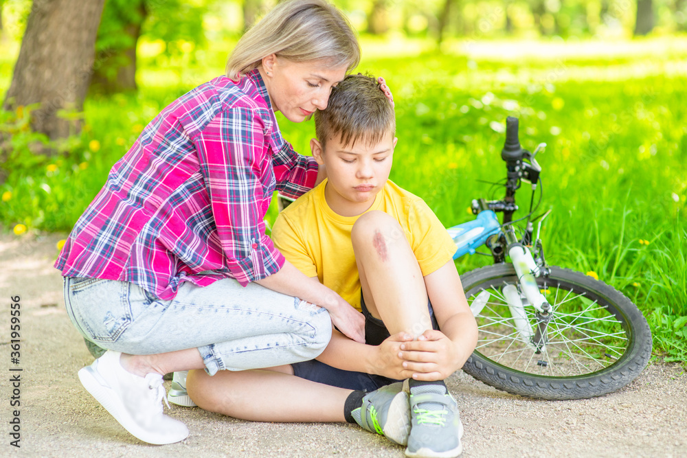 Mum comforting her son, who fell while riding a bicycle and scraped his knee