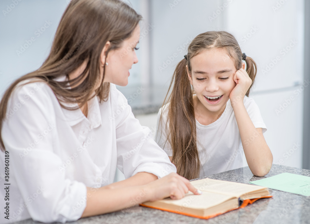 Young mother reads a book to her happy young daughter at home Young mother reads a book to her happy young daughter at home
