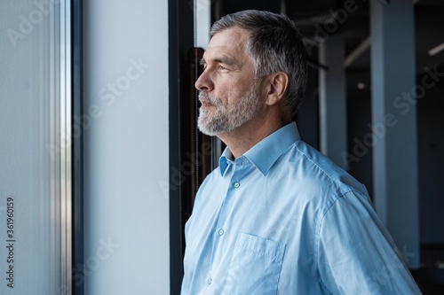 cheerful businessman looking at window while standing in office building.