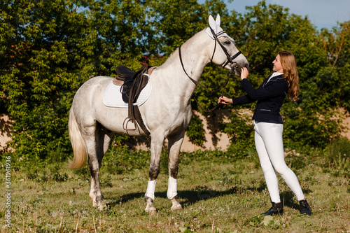 Girl rider strokes beautiful white horse