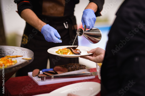 Fototapeta Naklejka Na Ścianę i Meble -  The chef serves the dish on a plate. Steak topping