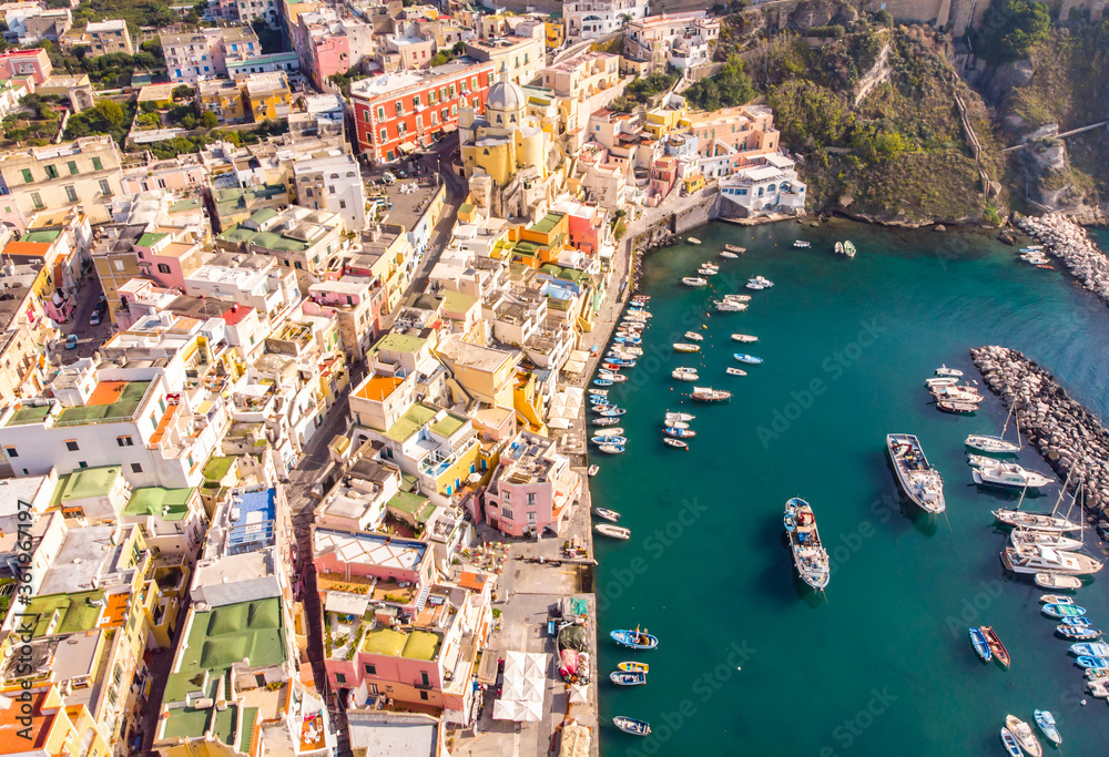 Aerial drone view of vibrantly colorful houses of Marina Corricella in sunny summer weather at Procida island, Italy