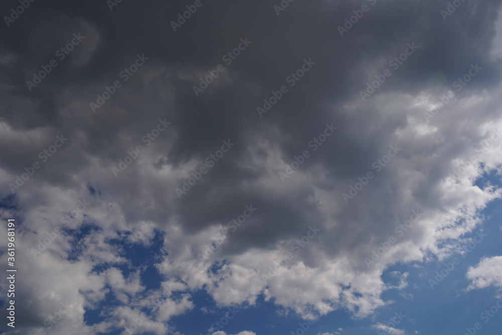 Blue sky with gray dark clouds on sunny day. Nature background.