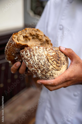 Baker holding fresh bread. He broke it in half.