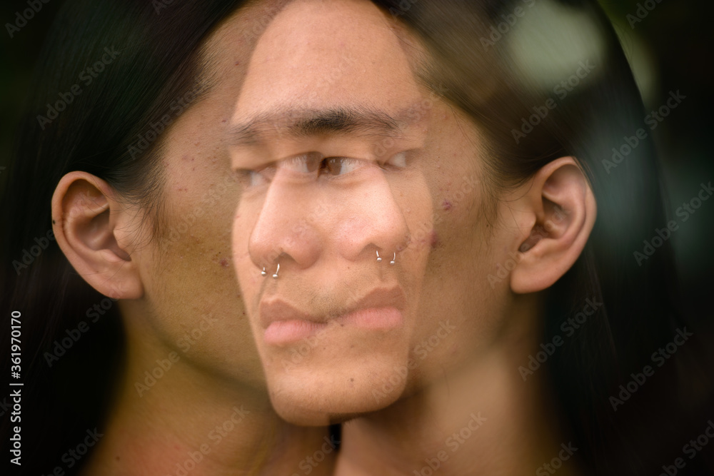 Obraz premium Young Asian man with long hair in the city with multiple exposure effect
