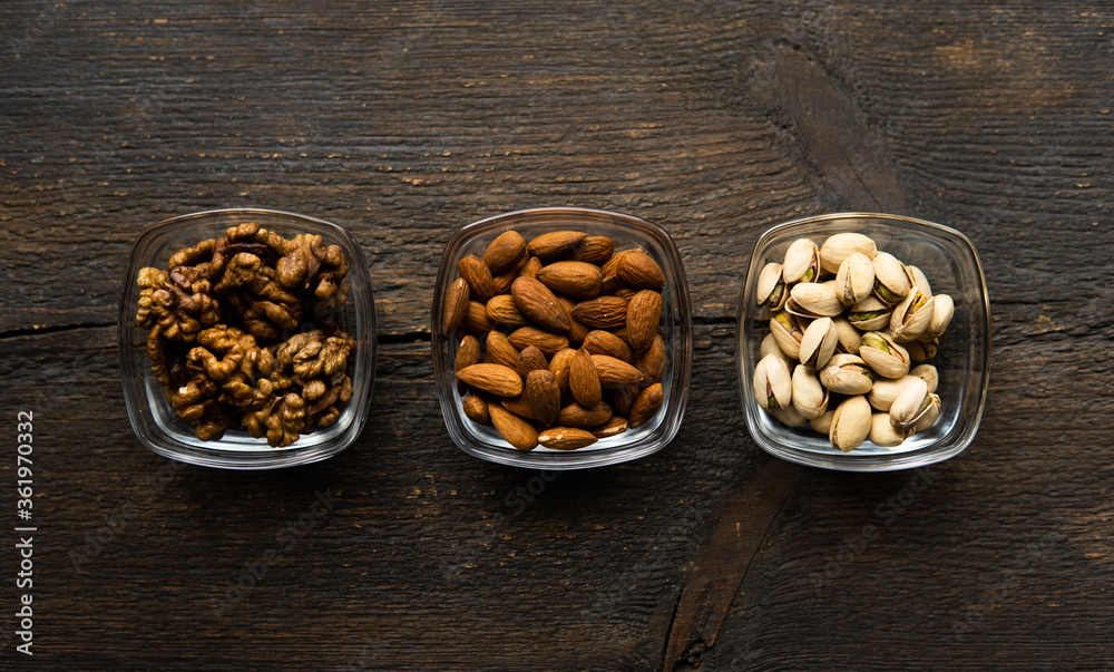 Almond, pistachio and walnut in a small plates which standing on a vintage wooden table. Nuts is a healthy vegetarian protein and nutritious food. Almond, pistachio and walnut in a small plates which standing on a vintage wooden table. Nuts is a healthy vegetarian protein and nutritious food.