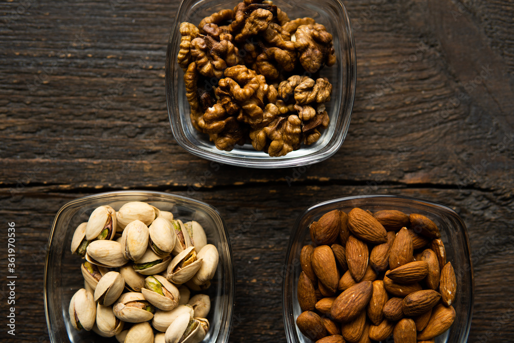 Almond, pistachio and walnut in a small plates which standing on a vintage wooden table. Nuts is a healthy vegetarian protein and nutritious food. Almond, pistachio and walnut in a small plates which standing on a vintage wooden table. Nuts is a healthy vegetarian protein and nutritious food.
