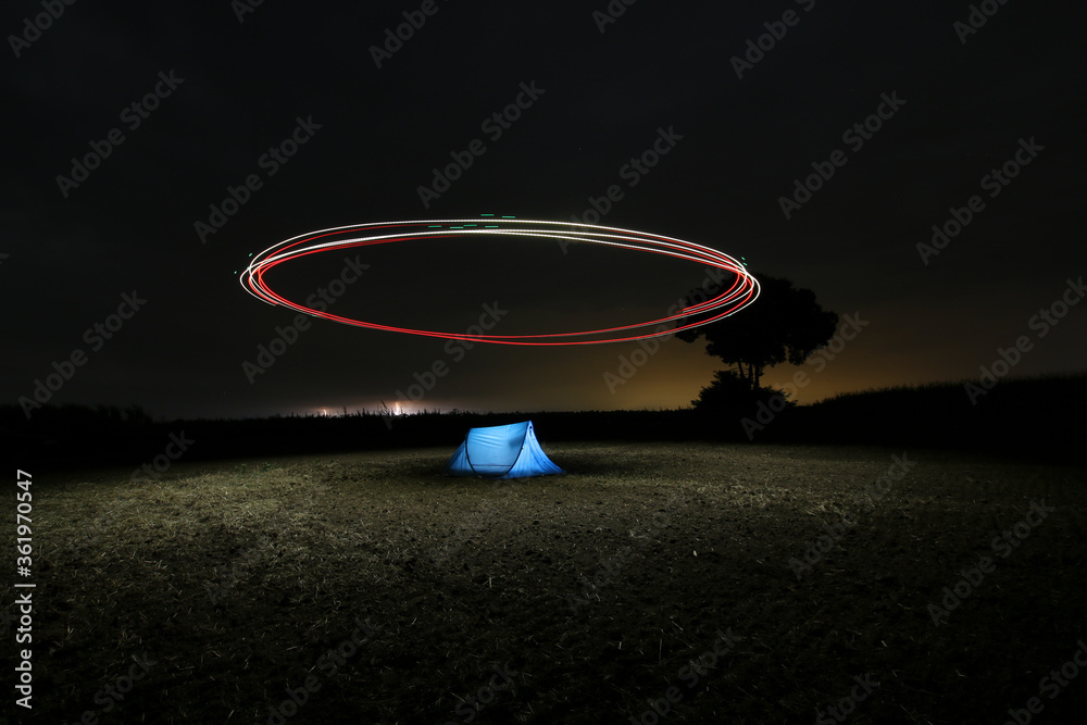 Night photo outdoors. There is a tent in the meadow above which the drone  circles. The long shutter speed photo contains grains. Light painting with  drone. Photos | Adobe Stock