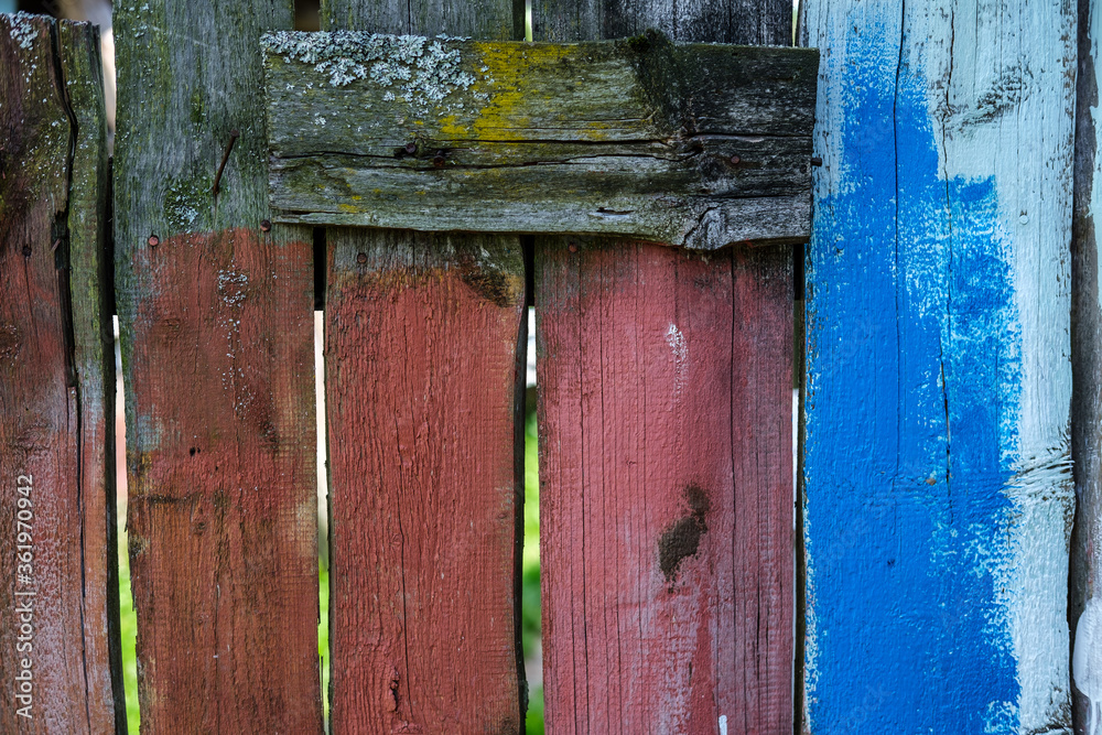Background in a rustic style from a fence made of wooden boards painted in different colors.