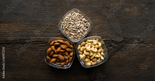 Almond, sunflower seeds and cashew in a small plates which standing on a vintage wooden table. Nuts is a healthy vegetarian protein and nutritious food.