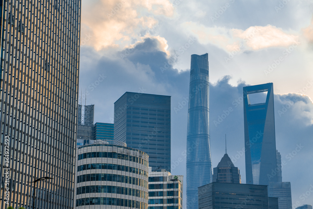 Obraz premium The modern skyscrapers in Lujiazui, the financial district in Shanghai, China, shot at sunset, on a cloudy day.