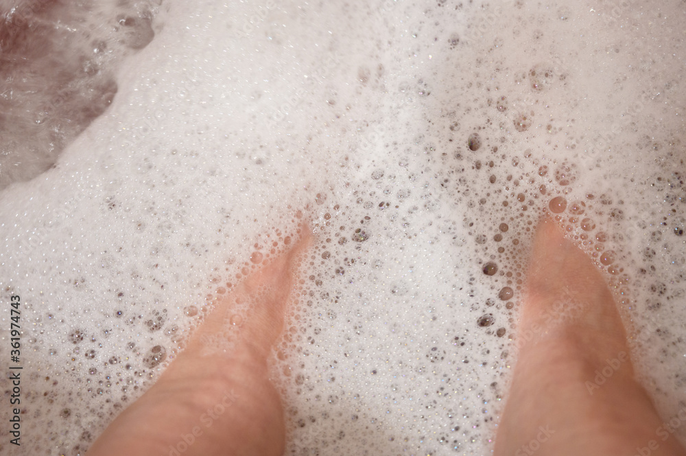 Fototapeta premium Woman bare feet in soap water at home in bathroom.